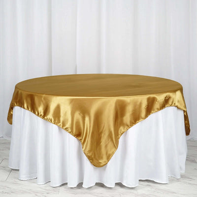 Gold satin tablecloth on a round table with white underneath.