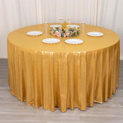 Round gold tablecloth draping over a table with decorative plates and centerpiece.