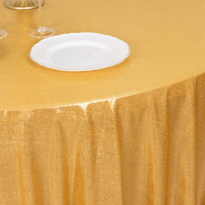 Gold tablecloth with elegant draping and a white plate set on a dining table.