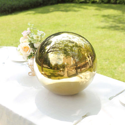 Gold decorative sphere on a table with floral arrangement in a garden setting.