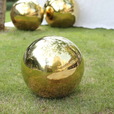 Reflective gold garden sphere on grass.