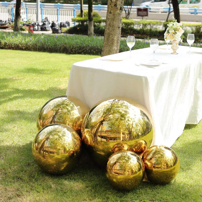 Gold decorative spheres near a table in a garden setting.