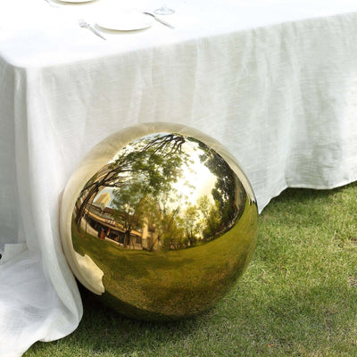 Reflective golden sphere beside a table in an outdoor setting.