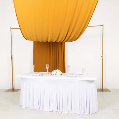 Elegant wedding table setup with white tablecloth and gold drapery.