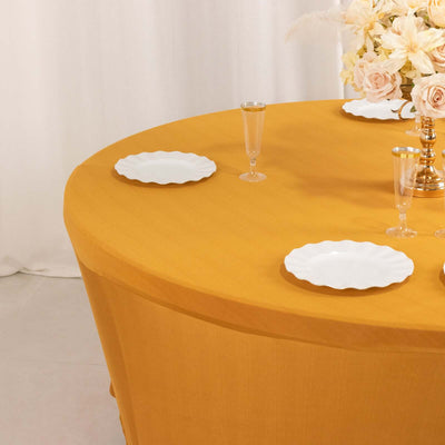 Yellow tablecloth on round table set with white plates and elegant floral arrangement.