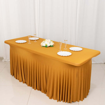 Yellow tablecloth draped over a table set for an event with plates and glasses.