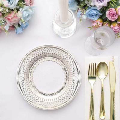 Elegant gold-rimmed plate with cutlery and floral decor on a white table setting.