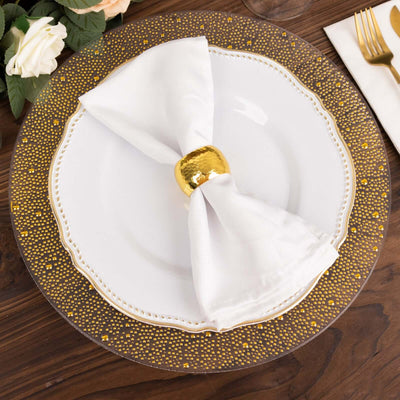 Elegant white napkin with gold ring on decorative plate setting.