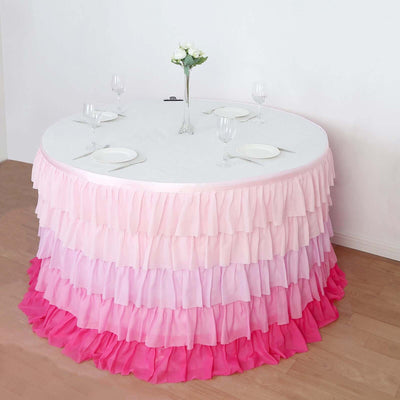 Round table with a gradient ruffled pink tablecloth, set for dining.