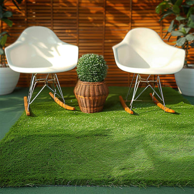 Two modern white rocking chairs on green grass with a potted plant in a wicker basket.