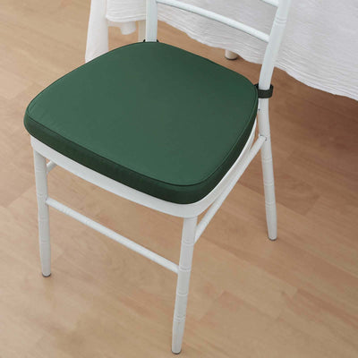 Green chair cushion on a white wooden chair, enhancing comfort and style.