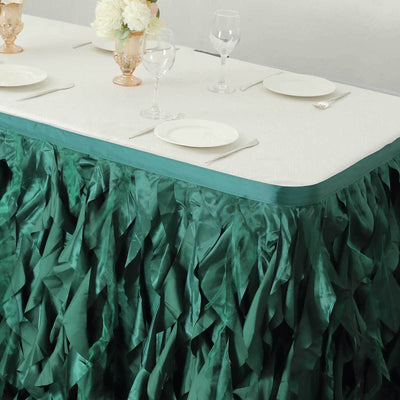Green ruffled tablecloth draped over a white table set for dining.