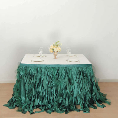 Elegant green table skirt draped over a white table with floral centerpiece.