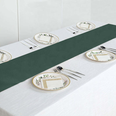 Elegant green table runner with decorative plates and cutlery on a dining table.