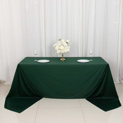Elegant green tablecloth with white plates and floral centerpiece for events.