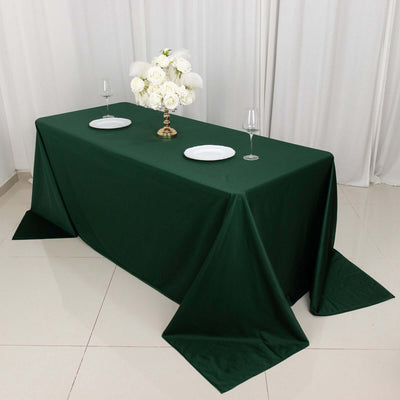 Elegant green tablecloth draped on a table set with plates and a floral centerpiece.