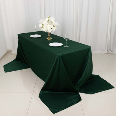 Elegant green tablecloth with white dinnerware and floral centerpiece.