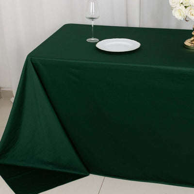 Green tablecloth draped over a table with a plate and wine glass on top.