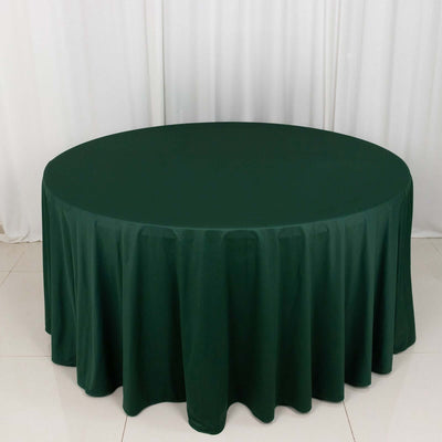 Round dark green tablecloth on a circular table in a studio setting.
