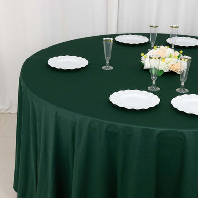 Elegant green tablecloth set with white plates and floral centerpiece.