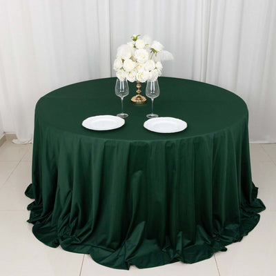 Green round tablecloth with elegant white flower centerpiece and plates.