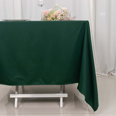 Green tablecloth draped over a white table with floral decor in the background.