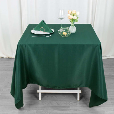 Green tablecloth draped over a table with decorative items and floral arrangement.