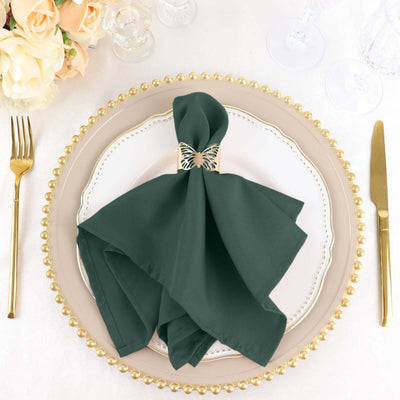 Green napkin with butterfly holder on an elegant plate setting.