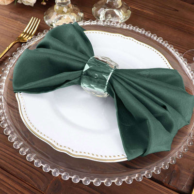 Elegant green napkin tied with a crystal napkin ring on a decorative plate.