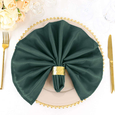 Elegant dark green napkin artfully arranged on a decorative plate.