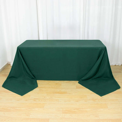 Green tablecloth draped over a rectangular table on a wooden floor.