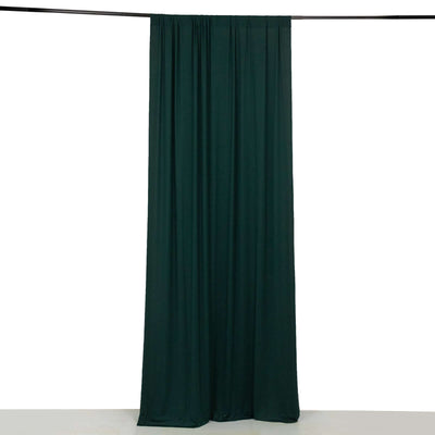 Dark green fabric curtain draped on a rod against a white backdrop.