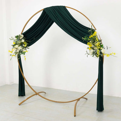 Green draped wedding arch with floral accents on a plain background.
