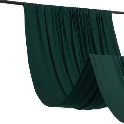 Green drapery fabric hanging on a rod, showcasing smooth folds and texture.