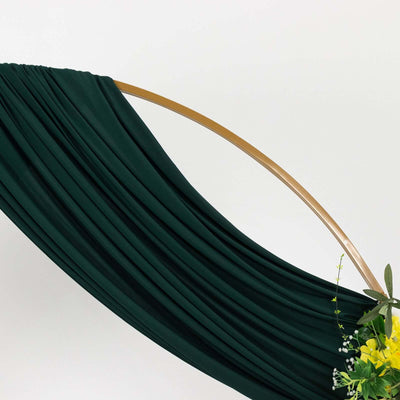 Green draped fabric with a wooden hoop and floral arrangement