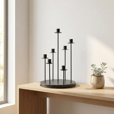 Modern black candle holder on wooden table beside small potted plant