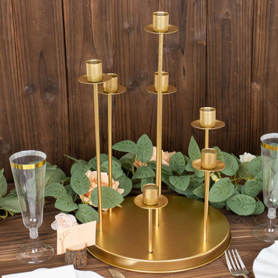 Gold candle holder centerpiece with multiple tiers and greenery accents.