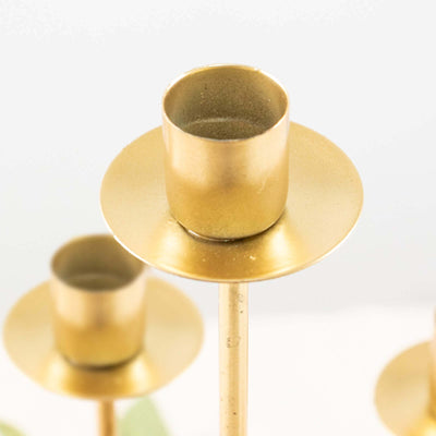 Gold candle holder with a sleek design on a plain backdrop.