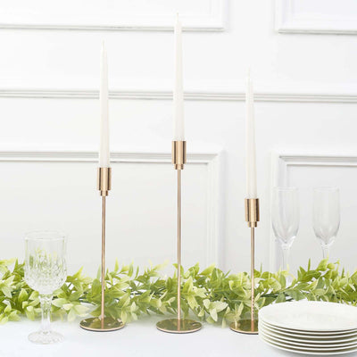 Elegant gold candle holders with white candles, styled on a table setting.
