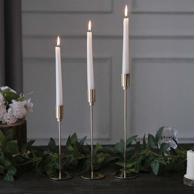 Elegant gold candle holders with white candles and greenery decor.