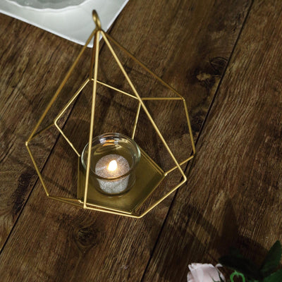 Geometric gold candle holder with tealight on a wooden table.