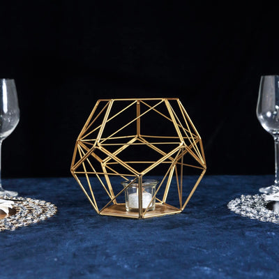 Gold geometric candle holder centerpiece on a dark table setting.