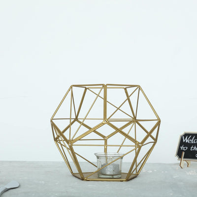 Gold geometric candle holder with glass insert on a plain background.