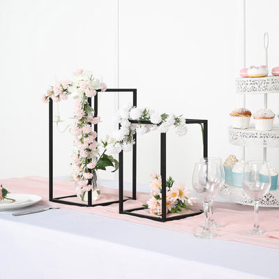 Decorative black flower stand with pink and white flowers on a table setting.
