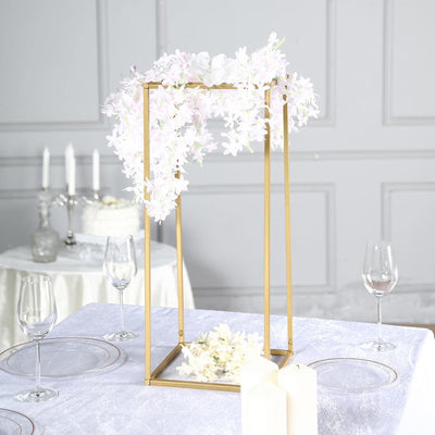 Floral centerpiece in gold frame on elegant dining table setting.