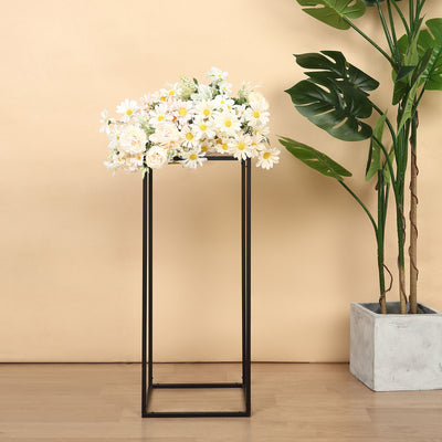 Floral arrangement on a modern black stand with green foliage.