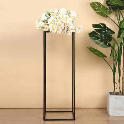 Floral arrangement in a modern black stand with greenery background.
