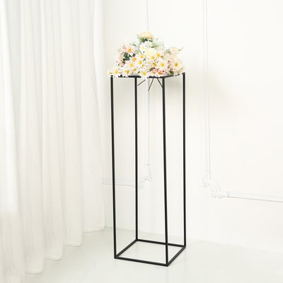 Black metal flower stand with a bouquet of flowers on top.
