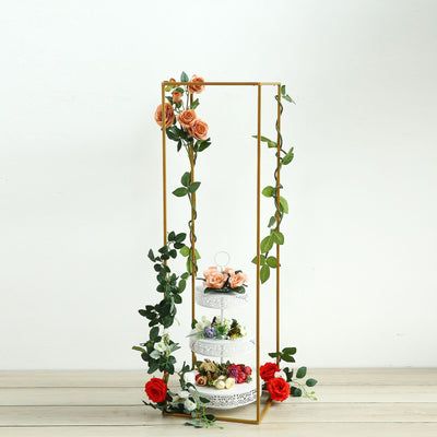 Elegant floral cake display with decorative gold stand and greenery.