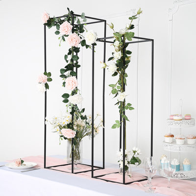 Floral display stands with roses and greenery in a styled setting.